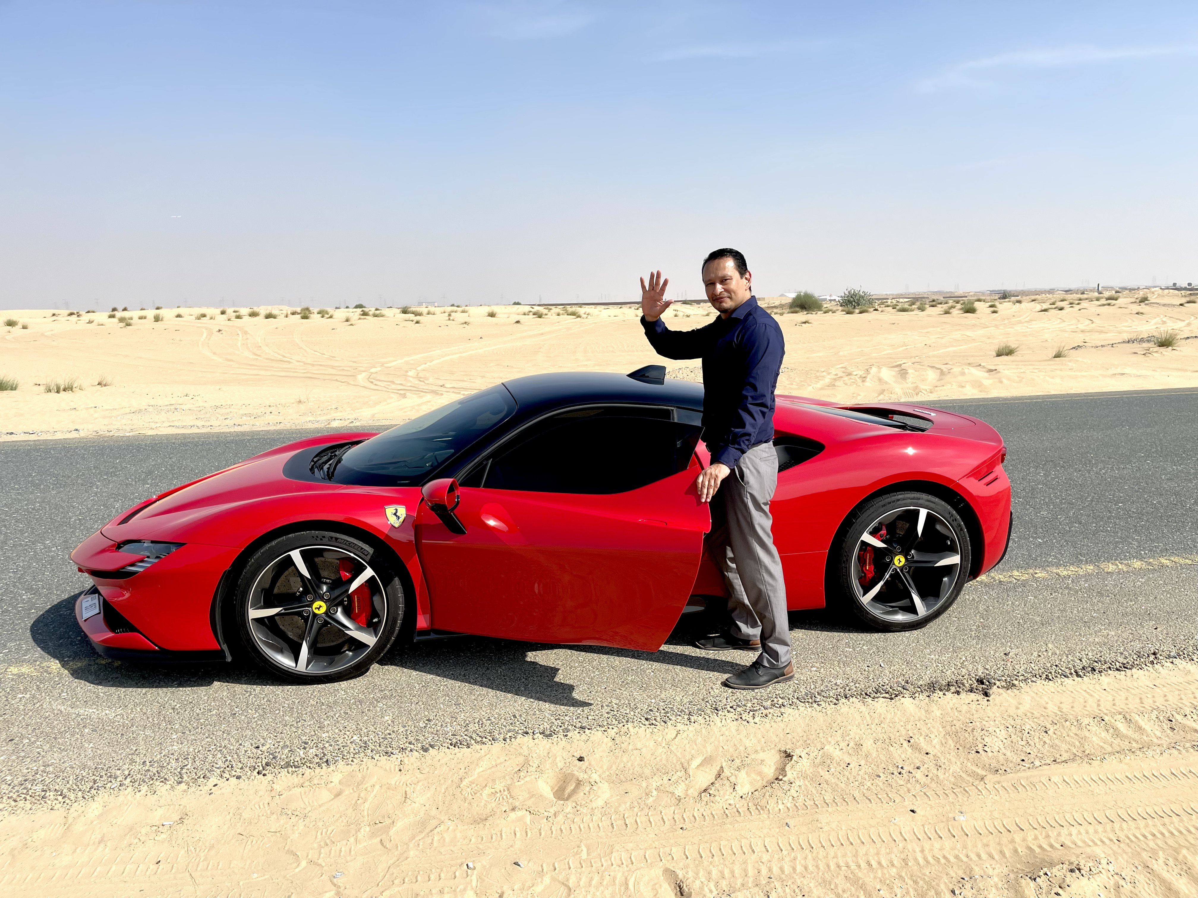 Gustavo junto a su Ferrari rojo en el desierto entre Dubái y Sharjah