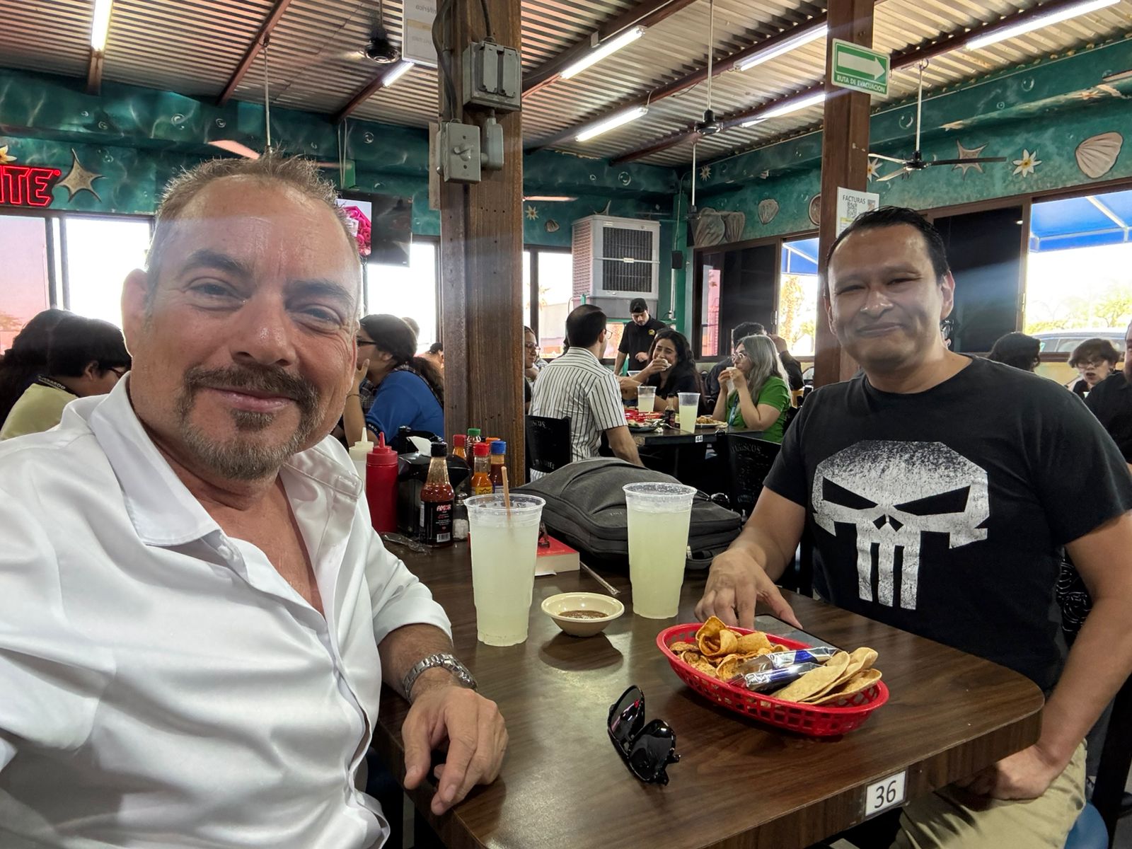 Gustavo Adolfo Carreño Monroy sonríe junto a su amigo DJ Robin en un restaurante de tacos de pescado